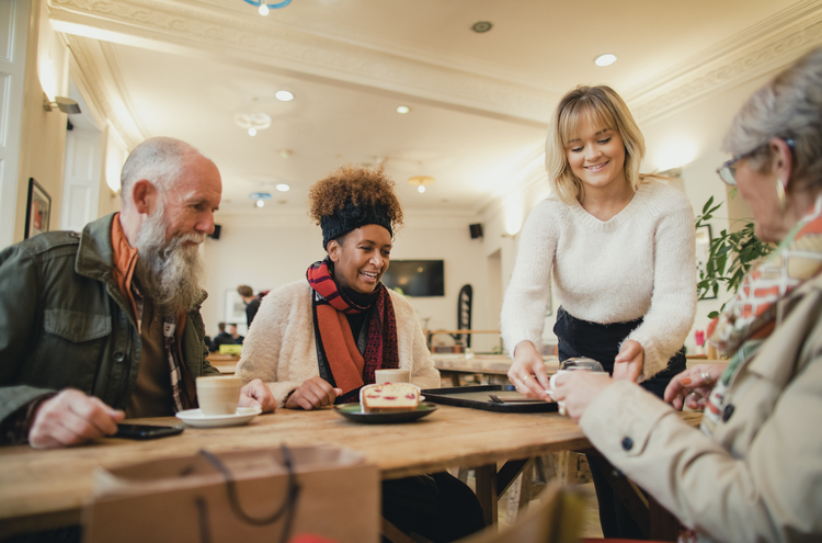 Restaurant waitress serving a table of three adults wearing winter gear