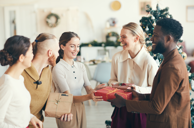 cheerful people exchanging presents during holiday work party