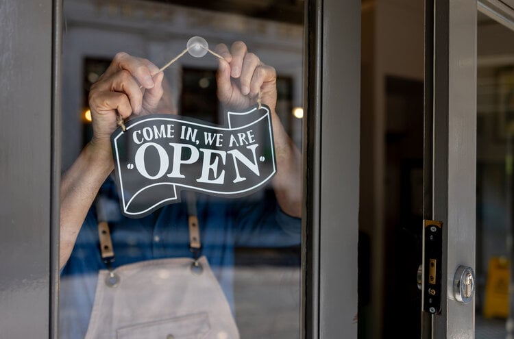 Close-up on a business owner hanging an open sign on the door of his restaurant for small business saturday