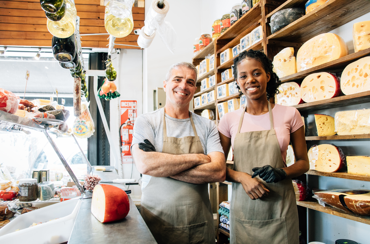 Small business owners with aprons at cheese counter